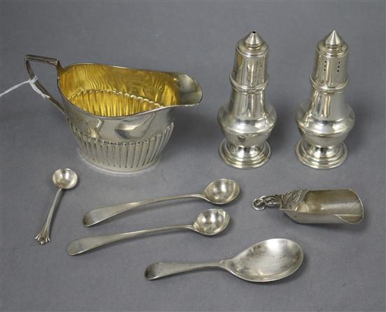 A silver cream jug, two silver pepperettes, three silver condiment spoons and two caddy spoons.